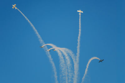 Low angle view of airshow against clear blue sky