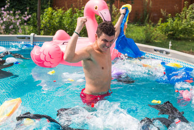 Full length of shirtless man playing in swimming pool