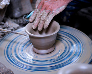 Cropped hands of man molding shape on pottery wheel