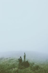 Rear view of men on field in foggy weather