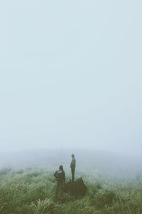 Men standing on grassy field during foggy weather