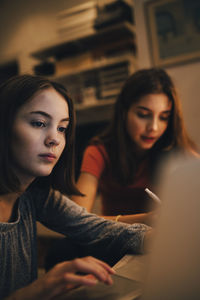 Close-up of female friends using laptop while studying at table