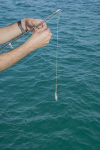 Cropped hands of man fishing in sea