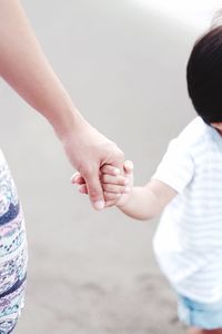Close-up of mother holding hands with child