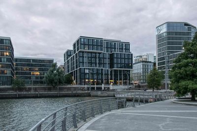 Modern buildings by road against sky in city