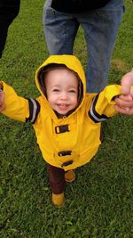 Midsection of father holding son hands while walking on grassy field