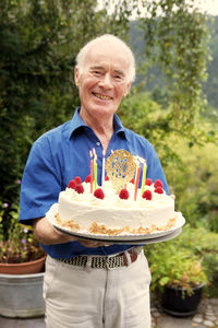 Senior man holding 80th birthday cake