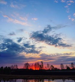 Silhouette trees on landscape against sky at sunset