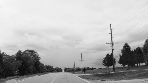 Road by trees against sky