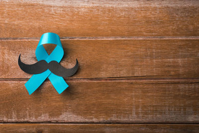 Close-up of aids ribbon with fake mustache on table