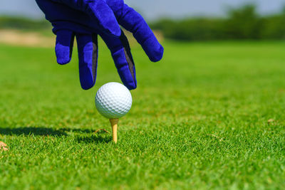 Hand golfer hold golf ball with tee ready to be shot at golf court.