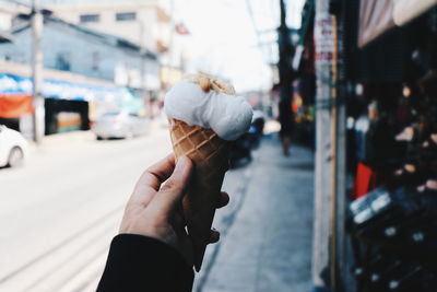 Close-up of hand holding ice cream on street