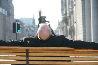Portrait of man relaxing on bench in city
