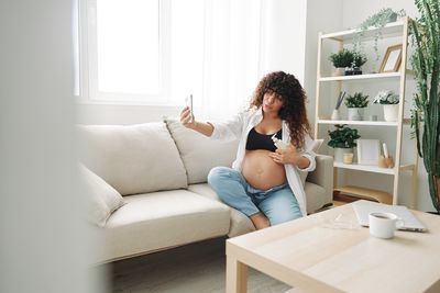 Young woman using laptop while sitting on sofa at home