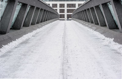 Empty road amidst buildings in city during winter