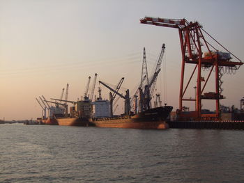 Cranes at commercial dock against sky