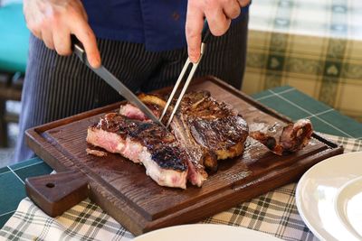 Close-up of man preparing food on barbecue grill