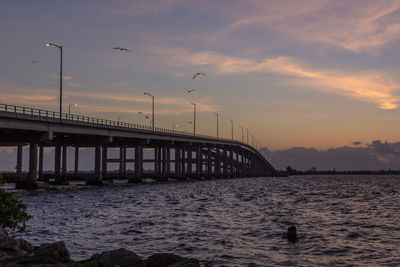 Bridge over river against sky during sunset