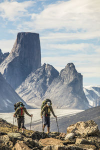 People on rocks against mountains