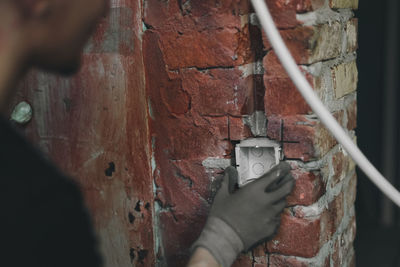 A young man installs a socket in the wall.