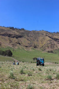 Tractor on field against clear blue sky