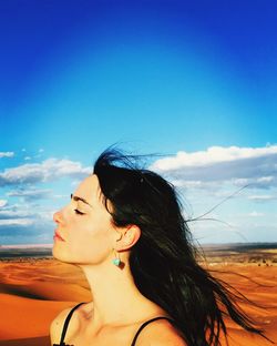 Portrait of woman looking away against blue sky