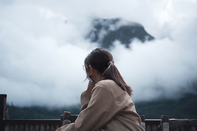 Side view of woman looking away against sky