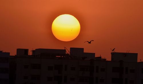 Silhouette of city against orange sky