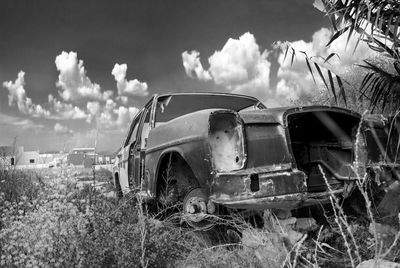 Abandoned car on field against sky