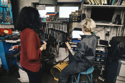 Female mechanic explaining customer over laptop at auto repair shop