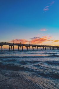 Bridge over sea against sky during sunset