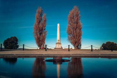 Panoramic view of trees by lake against blue sky