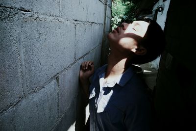 Young man standing by concrete wall