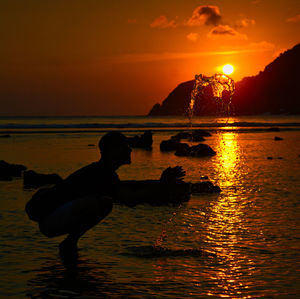 Silhouette man on beach against sky during sunset