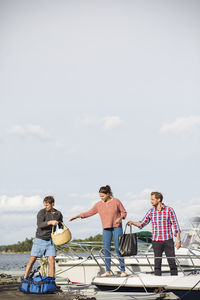 Friends boarding yacht against sky