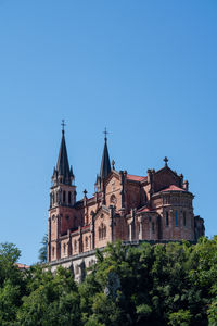 Basílica de santa maría la real de covadonga on the hill surrounded by the greenery