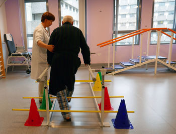 Physical therapist assisting senior man in exercising at nursing home