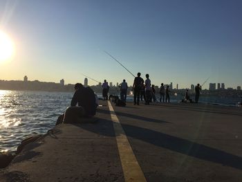 People by sea against clear sky