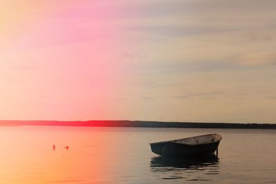 Boat in sea against sky during sunset