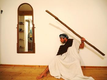 Man holding stick against wall