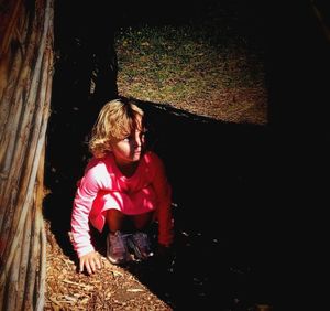 Girl looking away while standing against tree at night