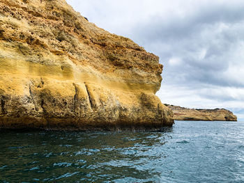 Rock formation by sea against sky