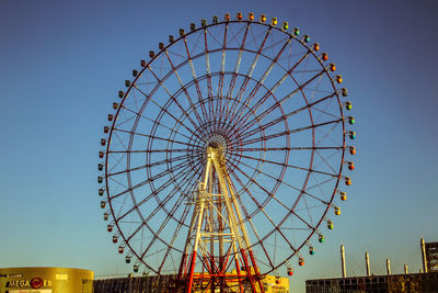 Low angle view of ferris wheel against clear blue sky