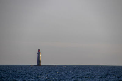 Lighthouse by sea against sky