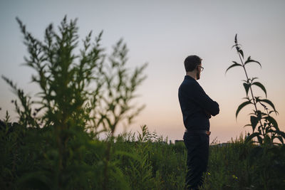 Businessman standing in rural field at sunset