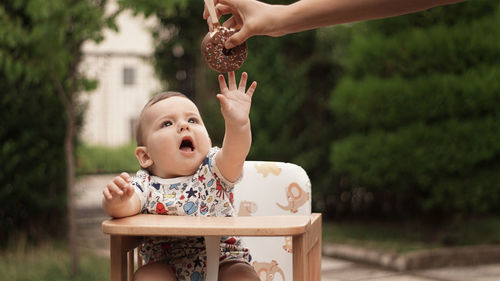 Cropped hand of mother giving ice cream to baby girl at park