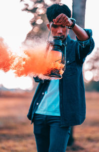 Midsection of man holding burning while standing on field