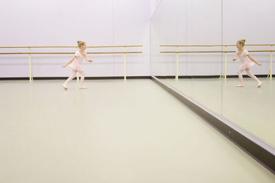 Girl practicing ballet in front of mirror at ballet studio