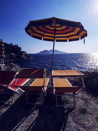 Deck chairs on beach against sky