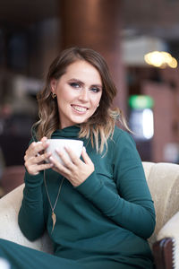 Smiling woman holding coffee cup at cafe